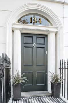 a black and white checkered floor with potted plants on the front door to a house