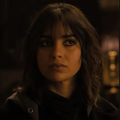 a close up of a person wearing a black jacket and looking at the camera with a serious look on her face