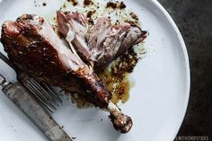 a white plate topped with meat next to a knife and fork