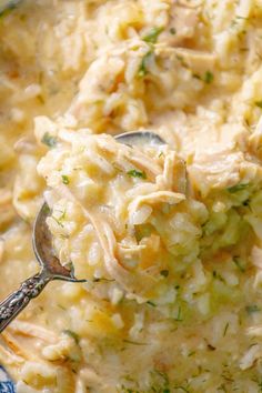 a spoon full of chicken and rice casserole is being held up over the bowl