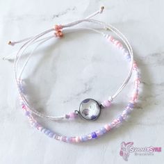 two bracelets with beads and a clock on them sitting on a marble table top