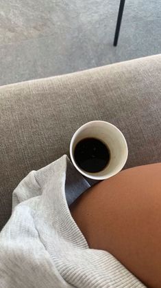 a cup of coffee sitting on top of a person's stomach