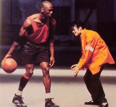 two men are playing basketball outside in the day time and one is wearing an orange jacket