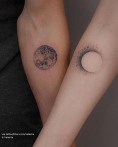 two people with tattoos on their arms holding each other's hands and the moon behind them