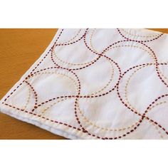 a white table cloth with red and gold circles on the front, sitting on a wooden surface