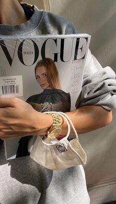 a woman is holding a magazine in her right hand and wearing a watch on her left wrist