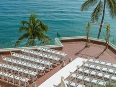 an aerial view of a wedding set up on the roof of a building overlooking the ocean