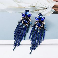 two pairs of blue beaded tasseled earrings on top of a white surface