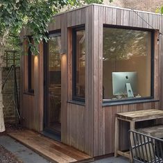 a small wooden building sitting next to a table and chair in front of a tree