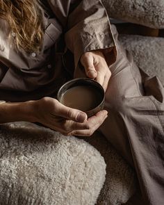 a person sitting on a couch holding a cup