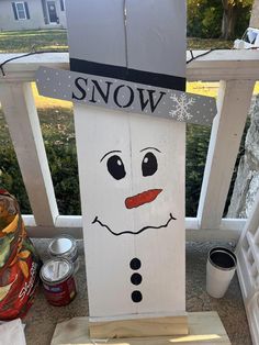 a wooden sign with a snowman face painted on it