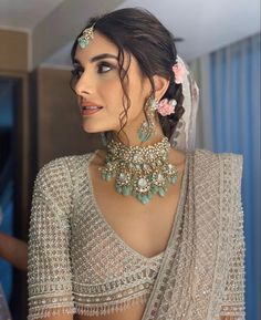 a woman in a white sari with flowers on her head and jewelry around her neck