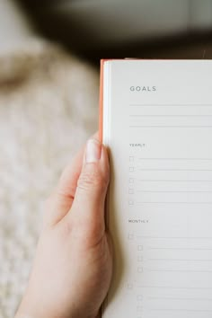 a person is holding an open planner in their hand with the words goals written on it