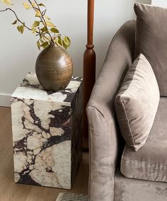 a marbled end table with a vase on it and a chair in the background