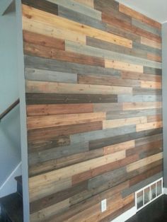 a wall made out of wooden planks in a living room with stairs leading up to the second floor