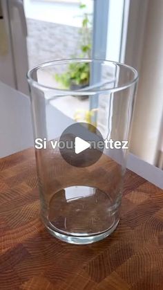 a clear glass sitting on top of a wooden table next to a window with the words sivou netez written in it