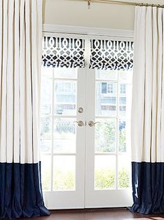 a living room with white and blue drapes on the windowsills, an arm chair in front of a door