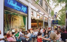 a group of people sitting on the sidewalk in front of a store