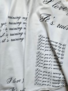 two white shirts with writing on them sitting on top of a table next to each other