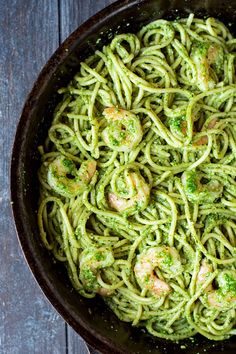 pasta with shrimp and pesto sauce in a skillet on a wooden table top