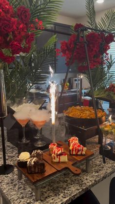 an assortment of desserts and drinks on a table with red flowers in the background