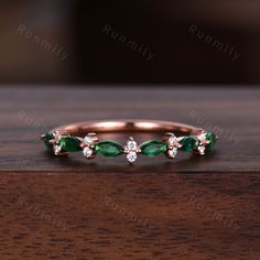 an emerald and diamond ring sitting on top of a wooden table