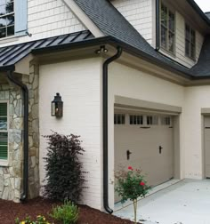 a white house with a black roof and two garage doors