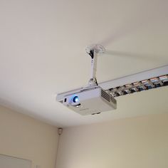 a ceiling mounted projector in the corner of a room