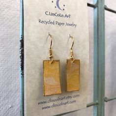 a pair of wooden earrings hanging from a hook on a metal rack in front of a sign