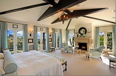 a large bedroom with a fireplace and lots of windows