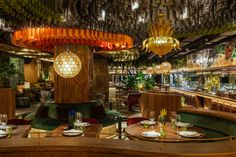 the interior of a restaurant with wooden tables and green velvet booths, gold chandeliers hanging from the ceiling