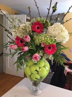 a vase filled with lots of flowers and apples