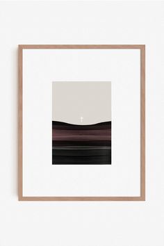 a white wall with a black and brown painting hanging on it's side next to a wooden frame