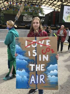 a girl holding a sign that says love is in the air