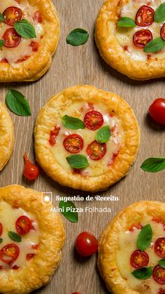 small pizzas with cheese, tomatoes and basil on a wooden table next to cherry tomatoes