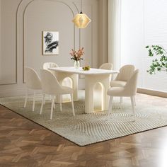 a white table and chairs in a room with hardwood floors, windows, and artwork on the wall