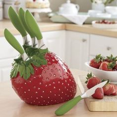 strawberries are being cut in half on a cutting board next to a bowl of strawberries