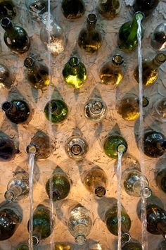 many wine bottles are lined up on the wall in front of each other with water running down them