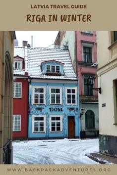 a blue and red building in the middle of a street with snow on the ground