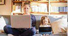 a woman and child sitting on a couch with laptops