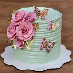 a green cake with pink flowers and butterflies on top