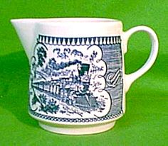 a blue and white coffee cup on a green tablecloth with an image of a train