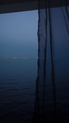 an ocean view from the inside of a boat at night with lights in the distance