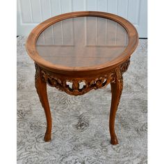 an antique wooden table with glass top on carpeted floor in front of white door