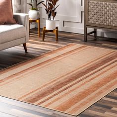 a living room area with a couch, chair and striped rug on the hardwood floor