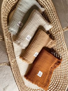 three pillows sitting on top of a wicker basket next to a pillow with tags