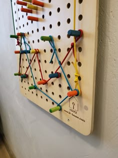 the peg board has many different colored pins on it and is attached to the wall