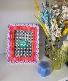 a decorative photo frame sitting on top of a table next to vases and flowers