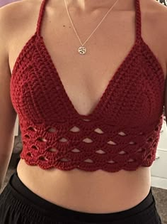 a woman wearing a red crochet top and black shorts is taking a selfie