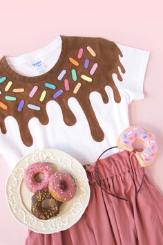 a white shirt with chocolate frosting and donuts next to a pink skirt on a pink background